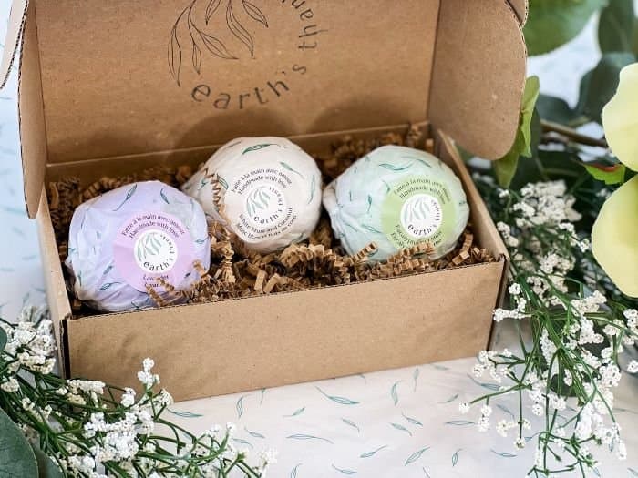 Three wrapped bath bombs in a kraft mailer box